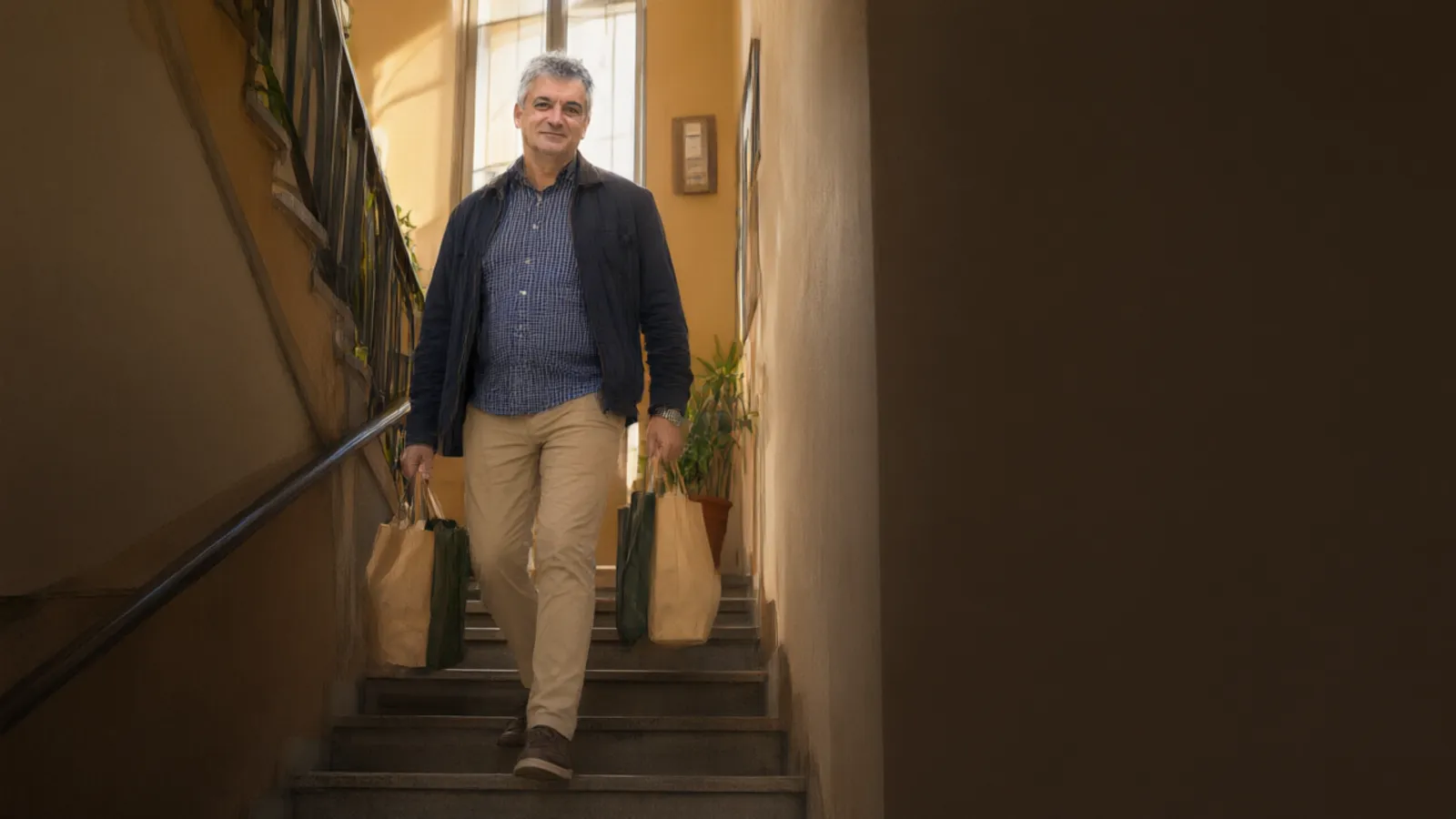 Roberto scende le scale con le borse della spesa